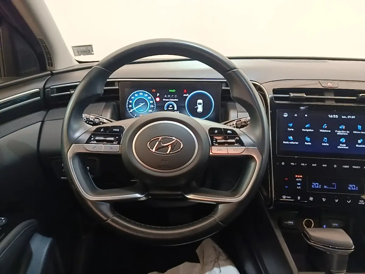 Vue intérieure centrée sur le volant noir du Hyundai Tucson 2021 avec tableau de bord digital et écran tactile.