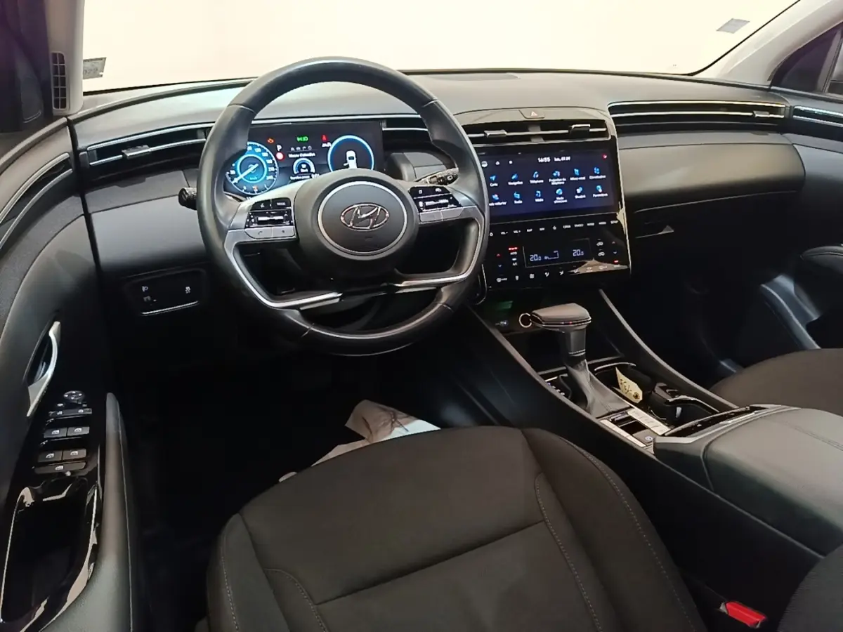 Vue intérieure avant du Hyundai Tucson 2021, tableau de bord noir avec écran tactile et volant multifonctions.
