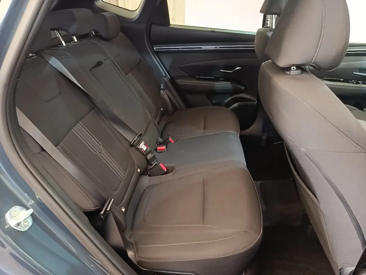 Vue intérieure côté gauche des sièges arrière noirs du Hyundai Tucson bleu, avec ceinture de sécurité visible.