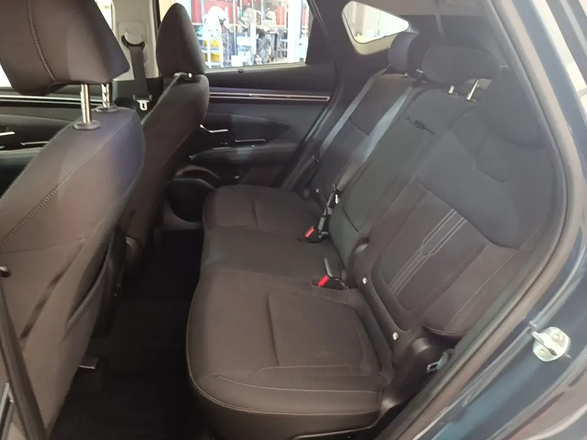 Vue intérieure côté droit des sièges arrière noirs du Hyundai Tucson 2021 hybride, avec ceintures et appuie-têtes visibles.