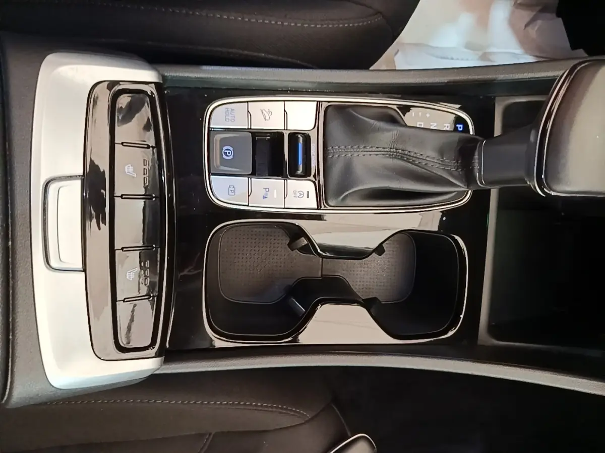 Vue rapprochée de la console centrale noire du Hyundai Tucson bleu 2021 avec levier de vitesses et commandes tactiles.