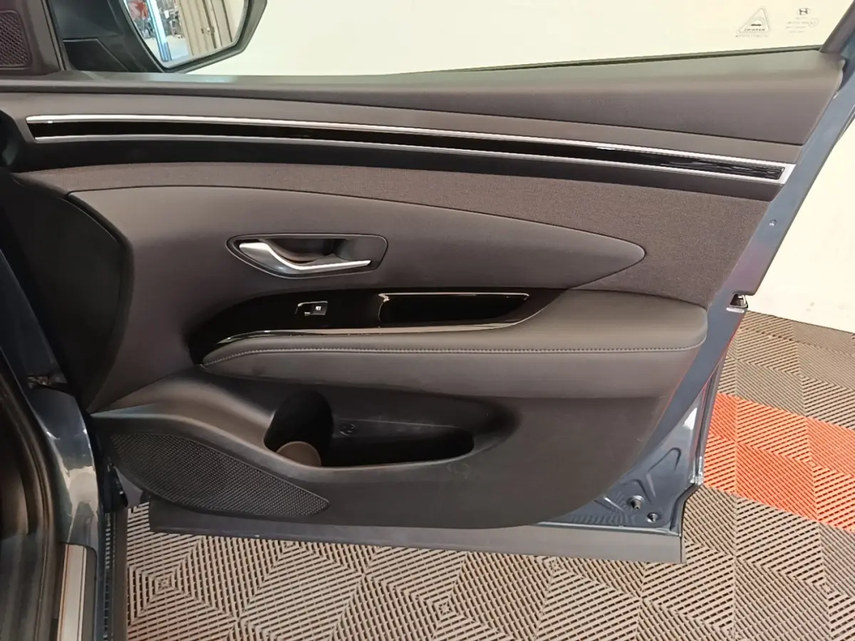 Vue intérieure de la porte avant gauche bleu foncé du Hyundai Tucson avec garniture noire et poignée argentée.