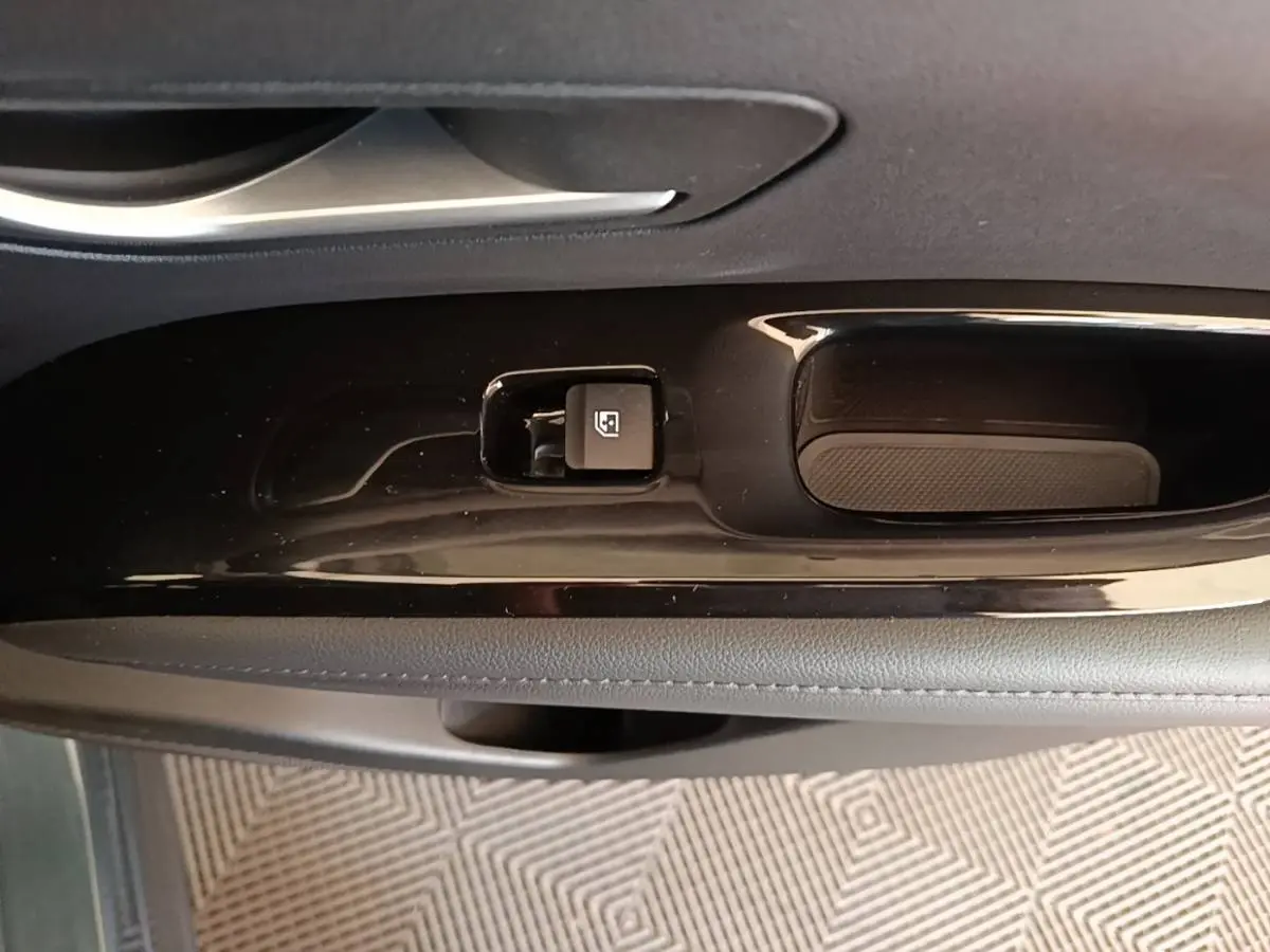 Gros plan sur la commande de verrouillage des vitres côté conducteur du Hyundai Tucson bleu, intérieur noir.