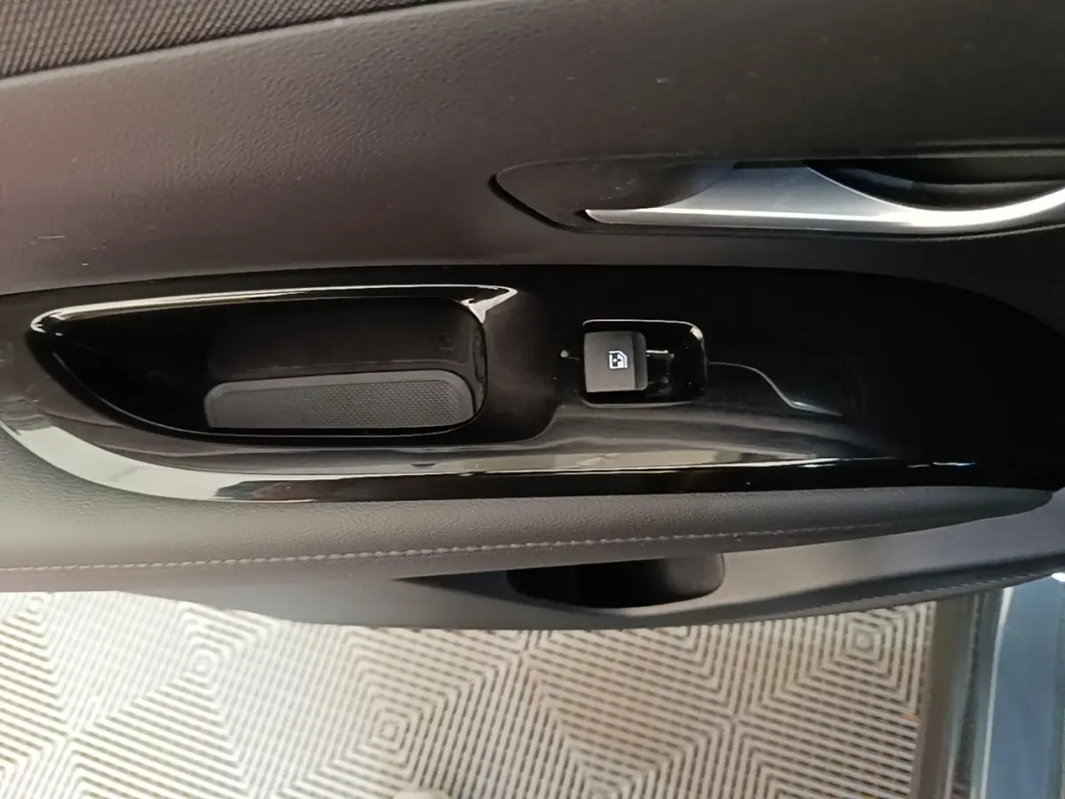 Gros plan sur la commande de verrouillage de porte côté conducteur, finition noire brillante dans l’habitacle du Hyundai Tucson bleu.