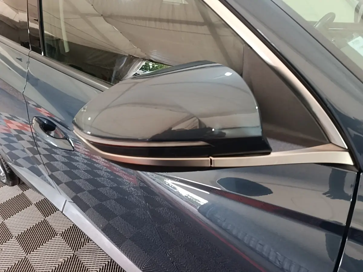 Rétroviseur côté conducteur du Hyundai Tucson bleu 2021, vue rapprochée sur la portière et poignée.