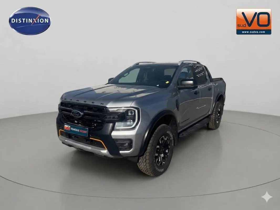 Ford Ranger gris en vue 3/4 avant droit avec barres de toit et jantes alliage noires.
