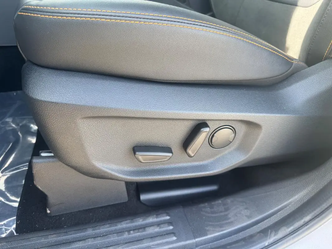 Gros plan sur les commandes de réglage électrique du siège avant droit en cuir noir avec surpiqûres orange du Ford Ranger gris 2025.