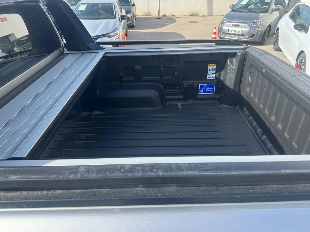 Vue rapprochée de la benne arrière grise du Ford Ranger 2025 avec barres de toit et ridelle ouverte.
