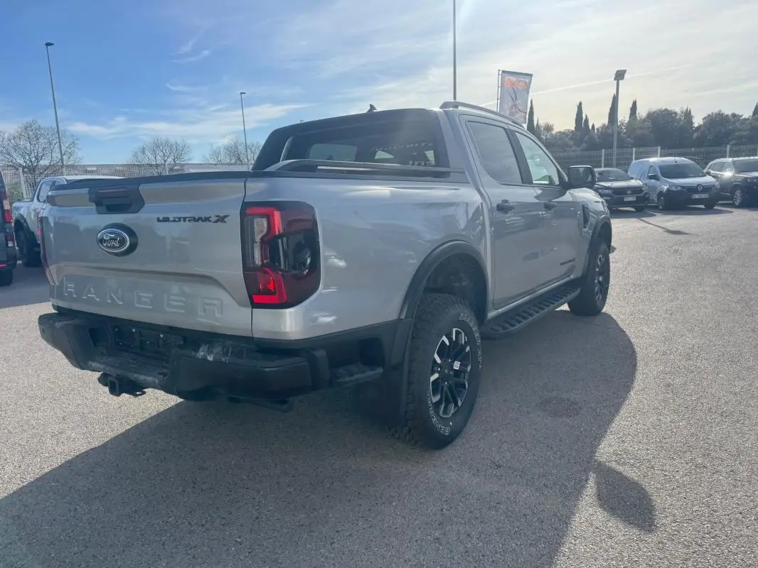 Vue 3/4 arrière droite d’un Ford Ranger gris Wildtrak X avec barres de toit et jantes alliage noires.