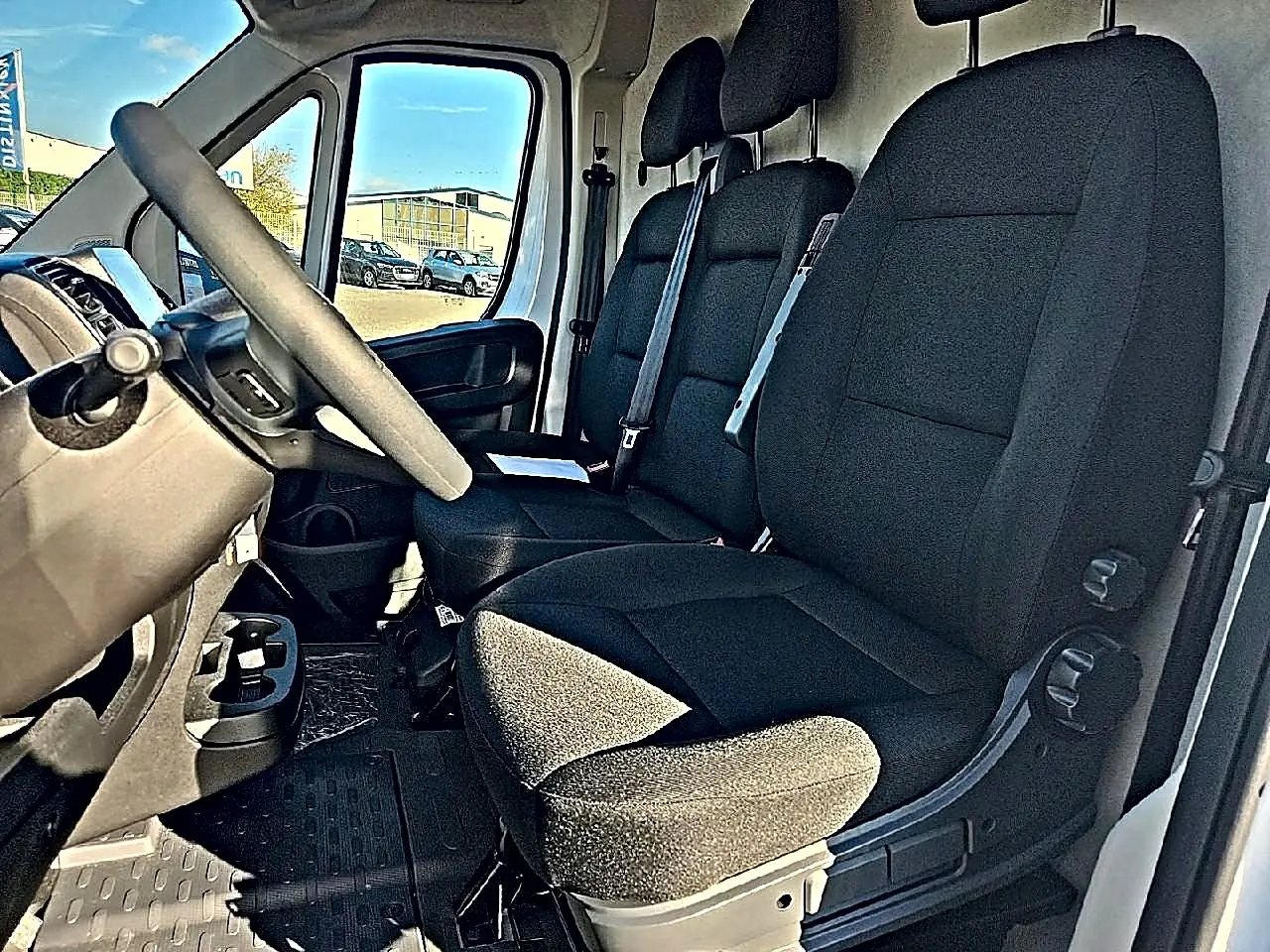 Vue intérieure côté conducteur du Peugeot Boxer Fourgon L2h2 2026, montrant les sièges noirs et le volant.