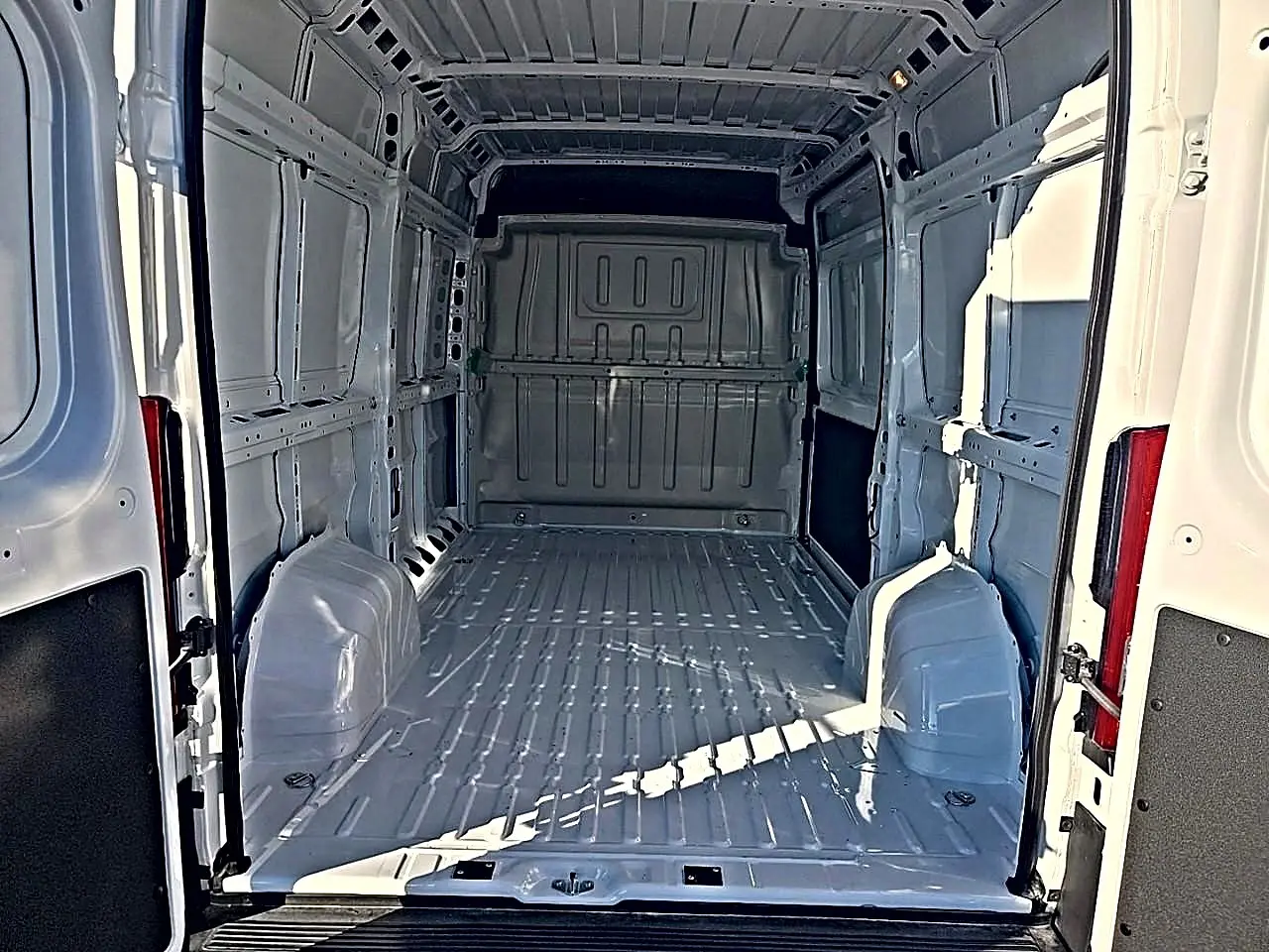 Vue intérieure arrière du fourgon blanc Peugeot Boxer L2h2 2026, montrant l'espace de chargement vide et la cloison pleine.