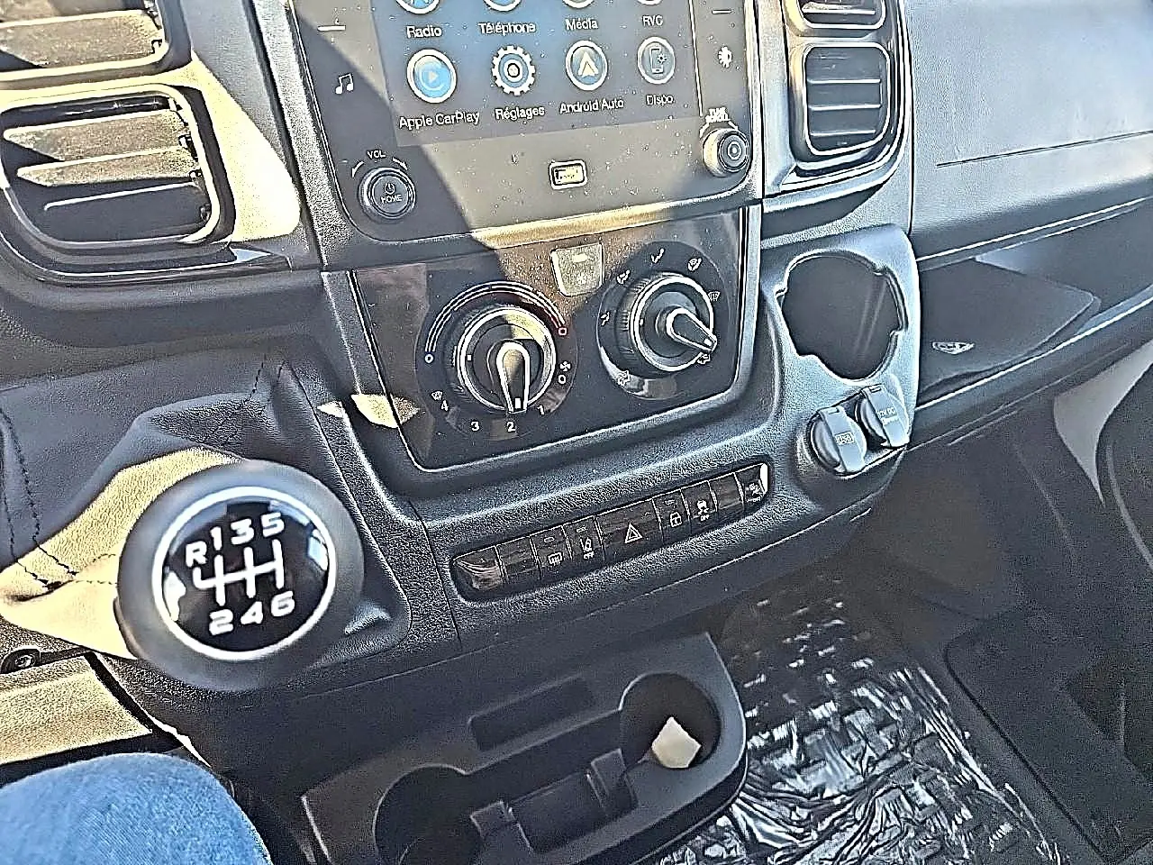 Gros plan sur la console centrale et levier de vitesses manuelle du Peugeot Boxer Fourgon blanc, avec commandes clim et écran tactile.