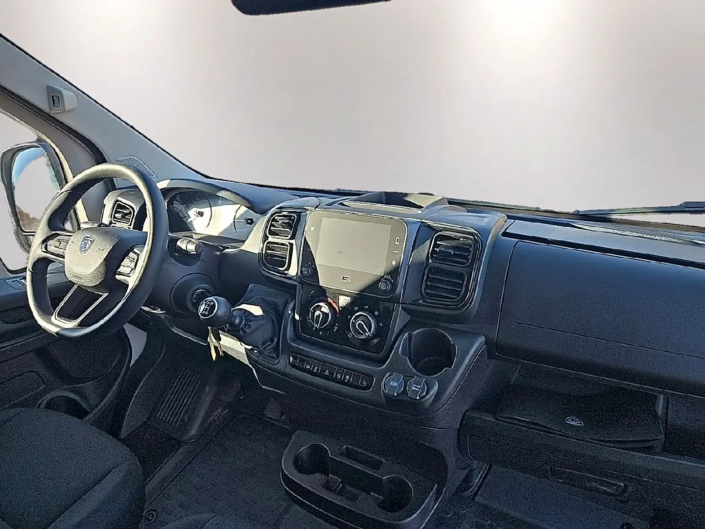 Vue intérieure du tableau de bord du Peugeot Boxer Fourgon blanc, avec volant, écran tactile et commandes manuelles visibles.