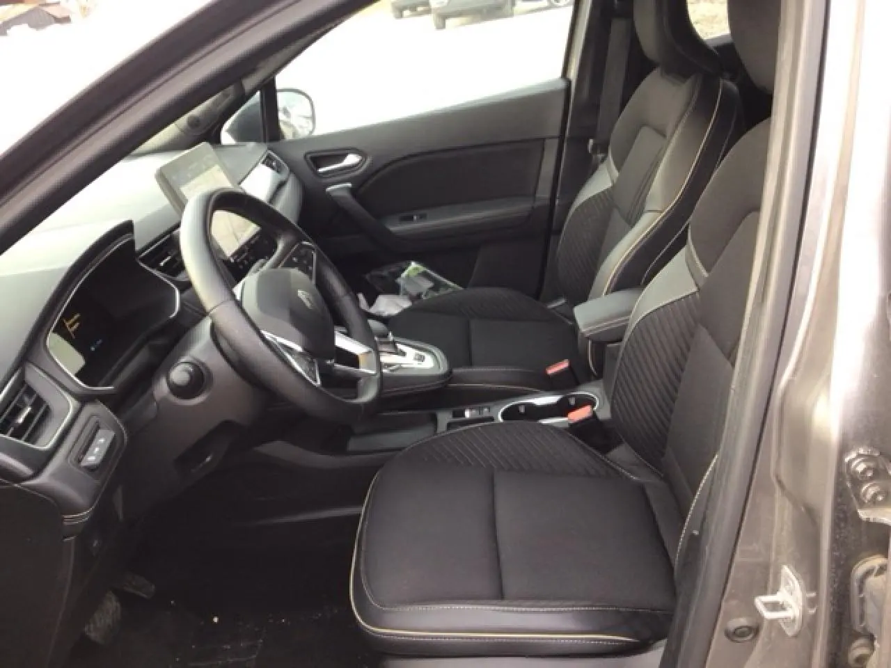 Vue intérieure côté conducteur du Renault Symbioz 2025, sièges noirs avec surpiqûres contrastées et tableau de bord moderne.