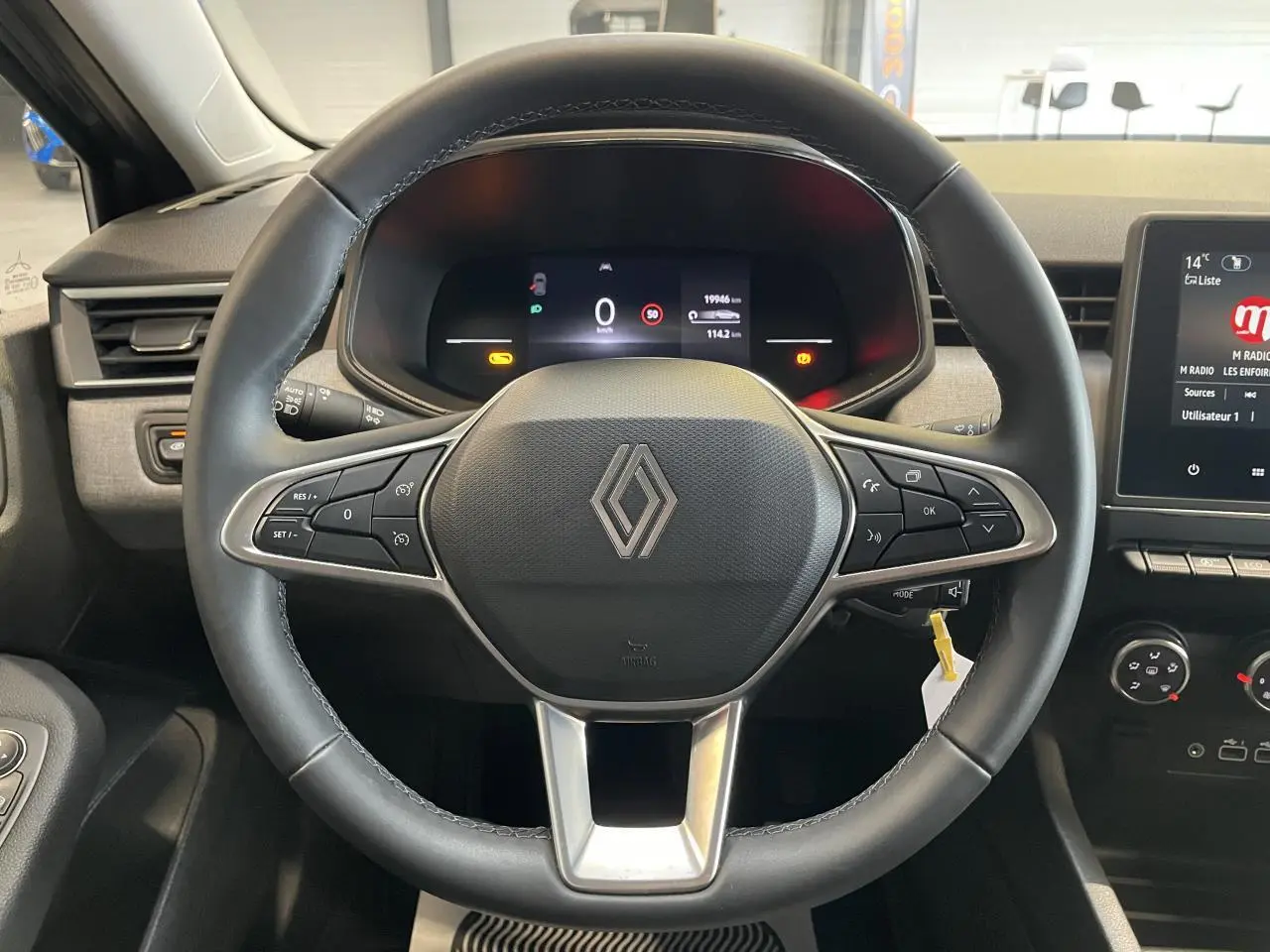 Vue centrée sur le volant noir de la Renault Clio 2024 avec tableau de bord numérique et commandes intégrées.