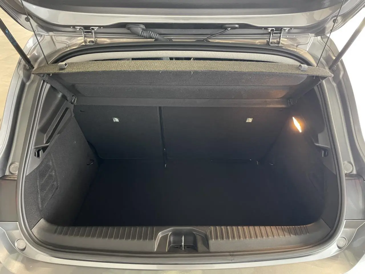 Coffre ouvert vu de dessus d'une Renault Clio 2024 gris foncé, avec éclairage intérieur et habillage noir.