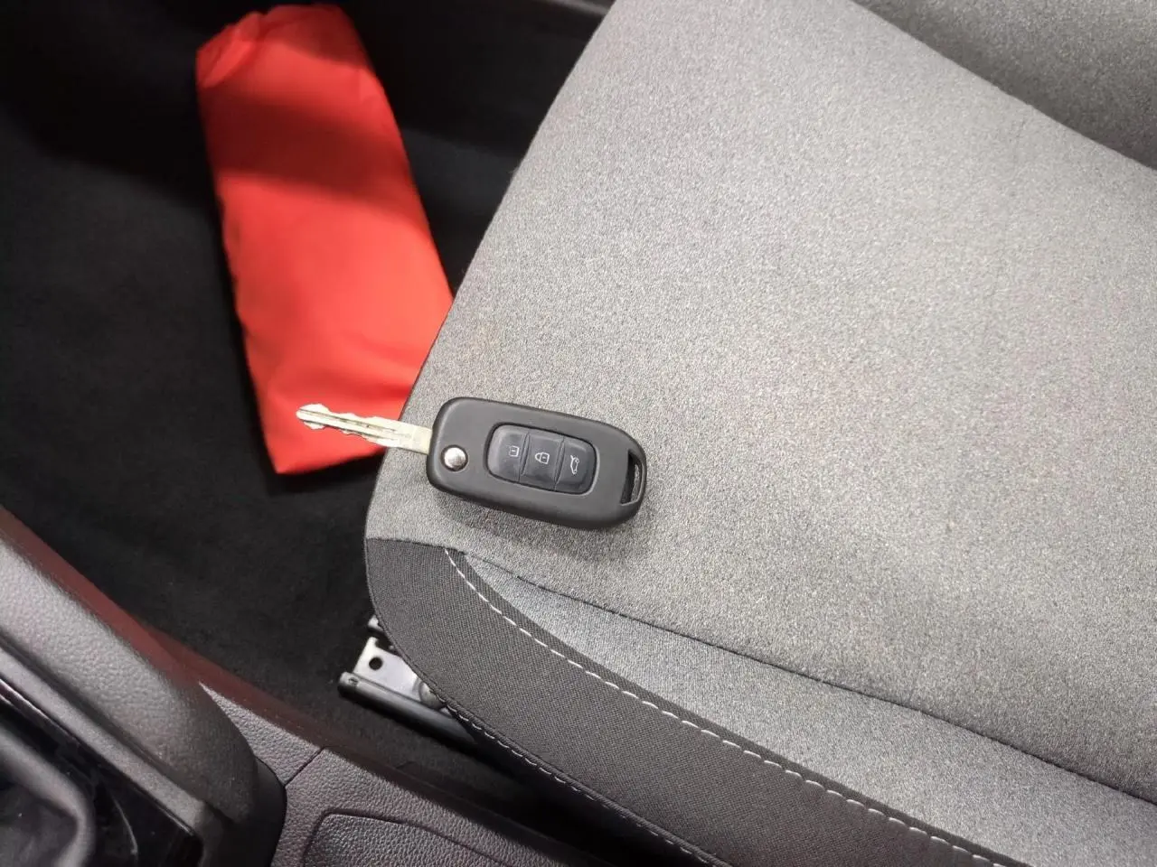 Gros plan sur la clé noire posée sur le siège tissu gris clair à motifs 3D de la Renault Clio 2024.