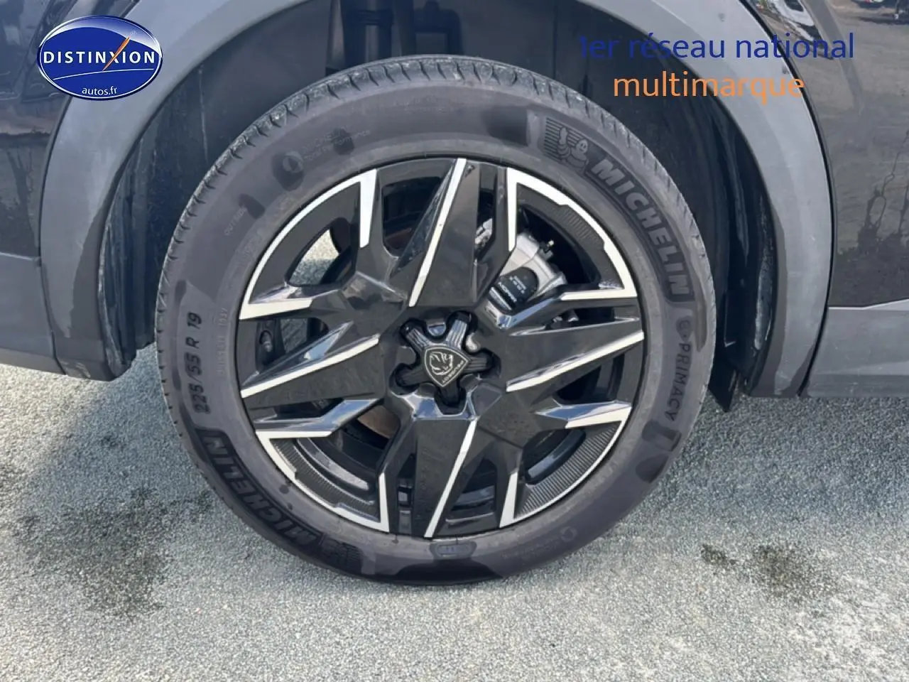 Gros plan sur la roue avant gauche noire d’un Peugeot 5008 Hybrid 145 allure e-dcs6 avec jante alu distinctive.