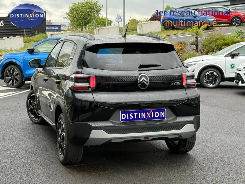 Vue 3/4 arrière droite d'une Citroën C3 électrique 2025 noire Perla Nera avec feux arrière LED et jantes alu noires.