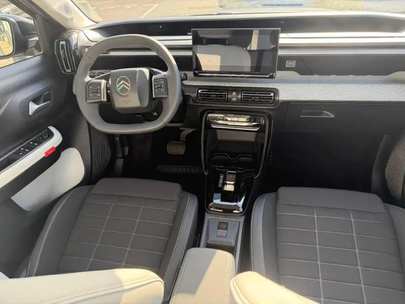 Vue intérieure avant de la Citroën C3 électrique 2025 noir Perla Nera avec tableau de bord moderne et écran tactile central.