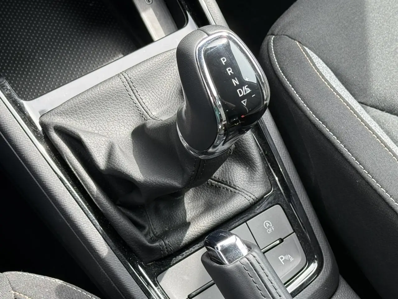 Gros plan sur le levier de vitesses automatique noir et chrome de la Skoda Scala TSI 116 DSG7, avec coutures visibles.