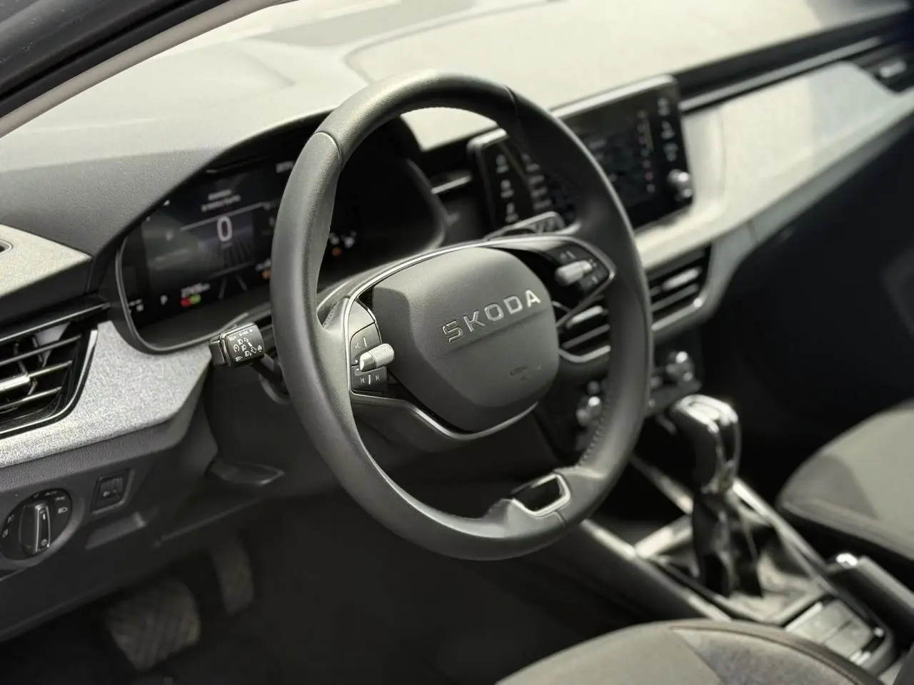Vue intérieure centrée sur le volant noir de la Skoda Scala 2025 avec tableau de bord digital et levier de vitesse automatique.