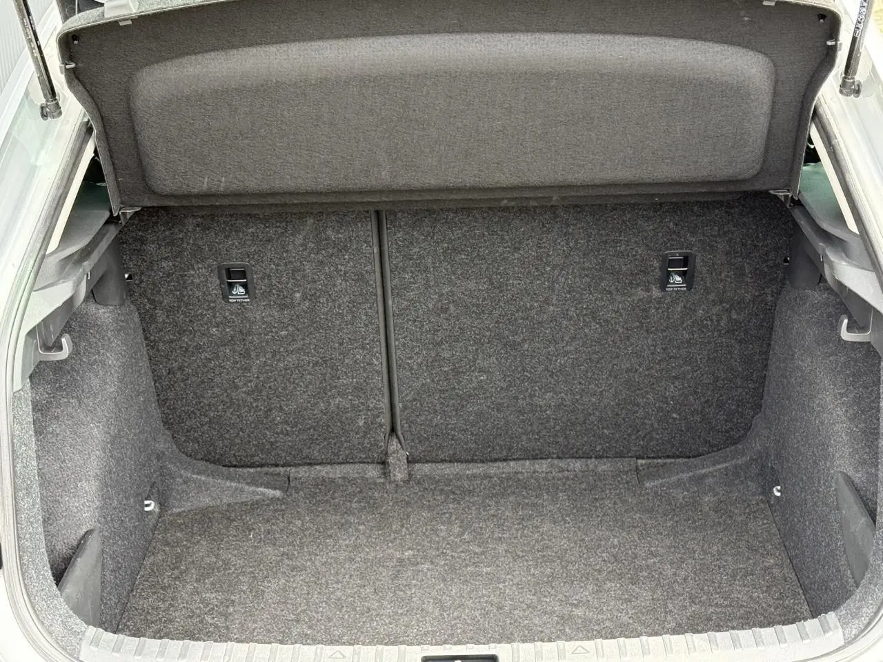 Coffre ouvert de la Skoda Scala TSI 116 DSG7 gris Reflex, montrant l'espace de chargement intérieur vide.