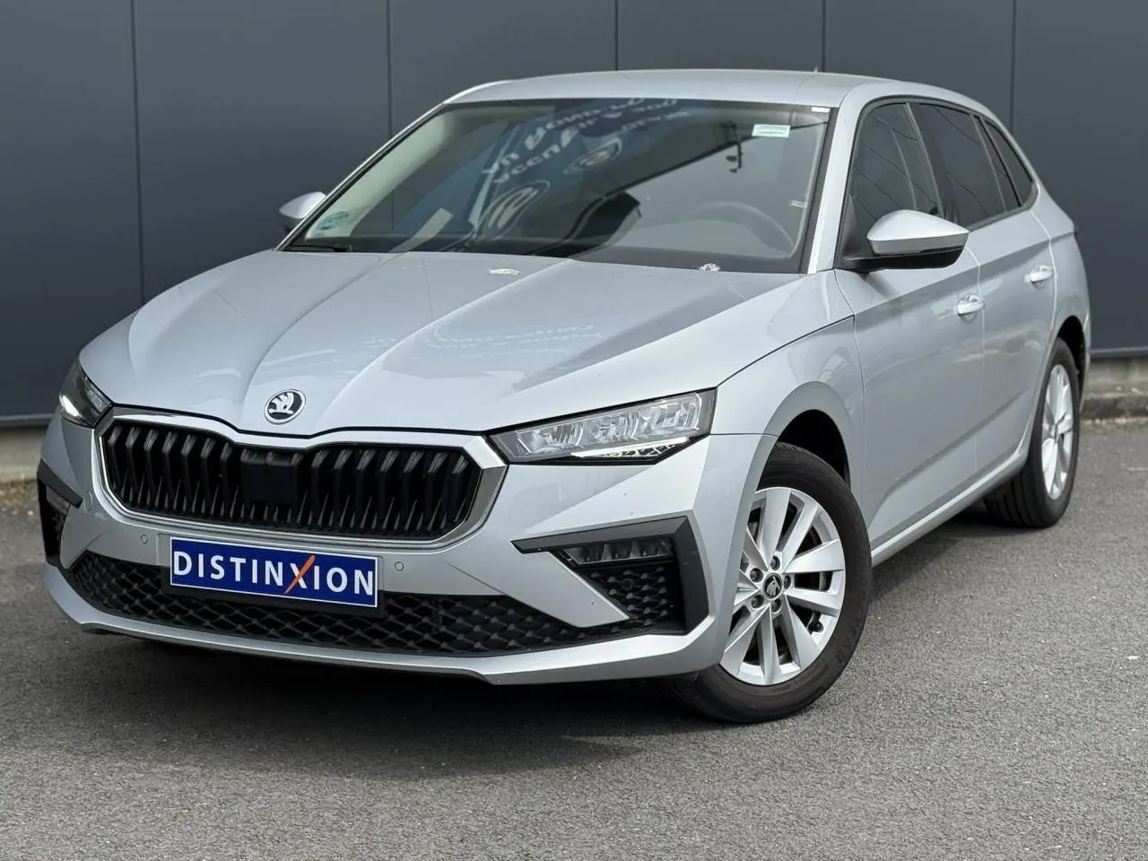 Vue 3/4 avant d'une Skoda Scala TSI 116 DSG7 gris Reflex avec calandre noire et jantes alliage 16 pouces.