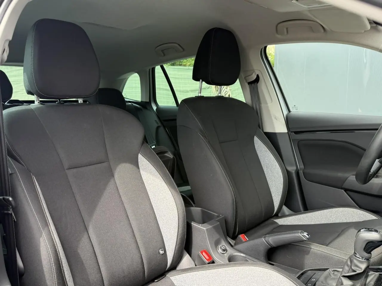 Vue intérieure côté avant droit du Skoda Scala TSI 116 DSG7, sièges tissu noir et gris avec surpiqûres contrastées.