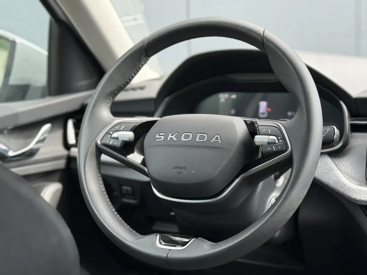 Vue rapprochée du volant cuir multifonctions SKODA de la Scala TSI 116 DSG7, avec tableau de bord numérique en arrière-plan.