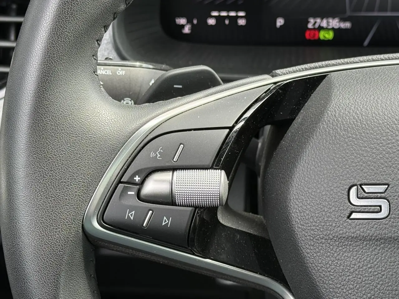 Gros plan sur la partie gauche du volant noir de la Skoda Scala 2025 avec commandes audio et molette métallique.
