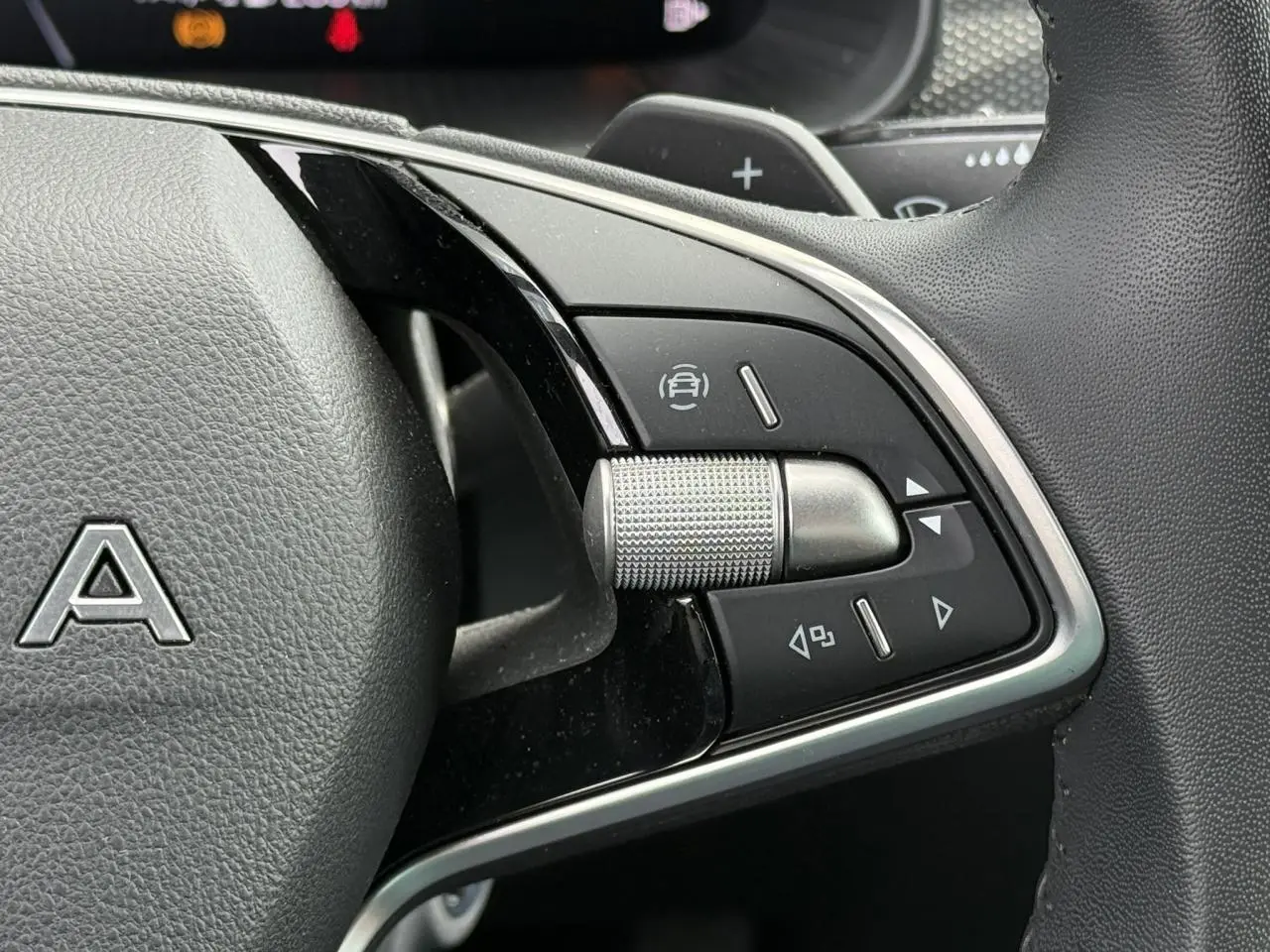 Gros plan sur les commandes multifonctions à droite du volant en cuir noir de la Skoda Scala TSI 116 DSG7 Sélection.