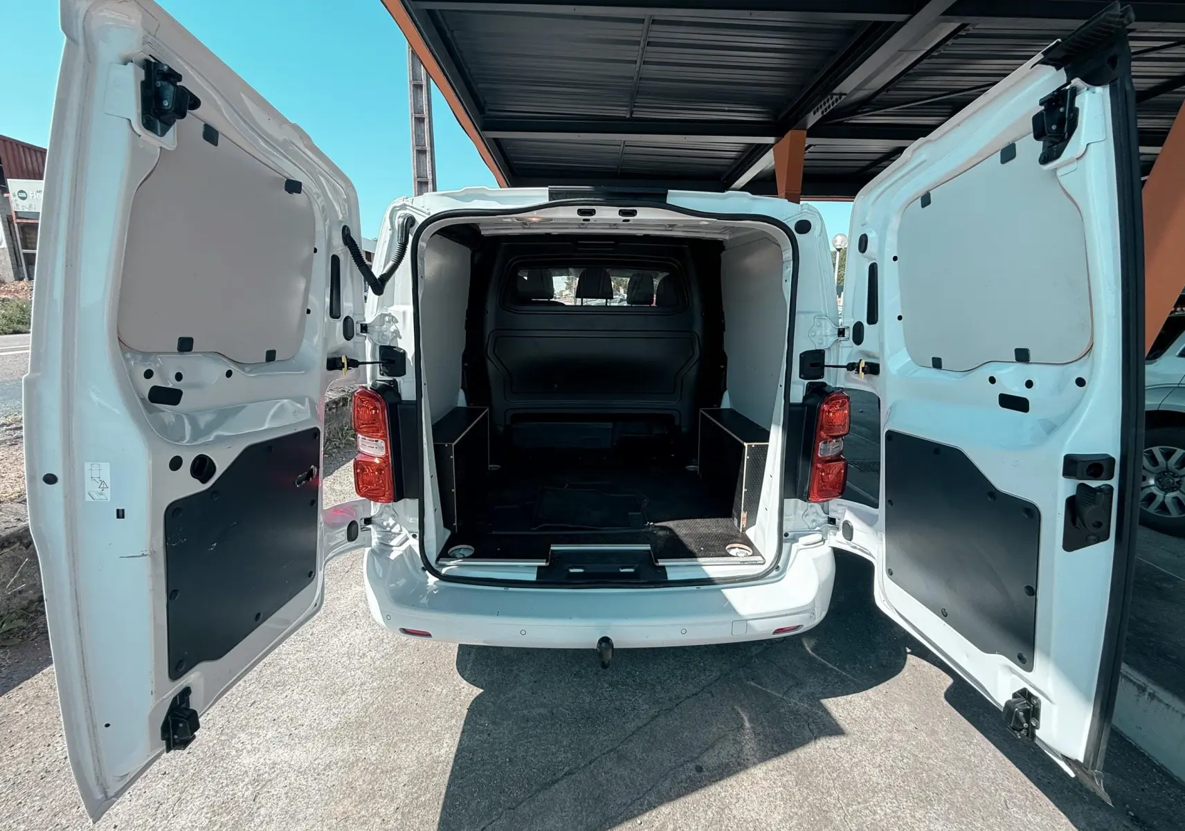 Vue arrière ouverte du Peugeot Expert cabine approfondie blanc, montrant l'espace de chargement vide et les portes battantes.