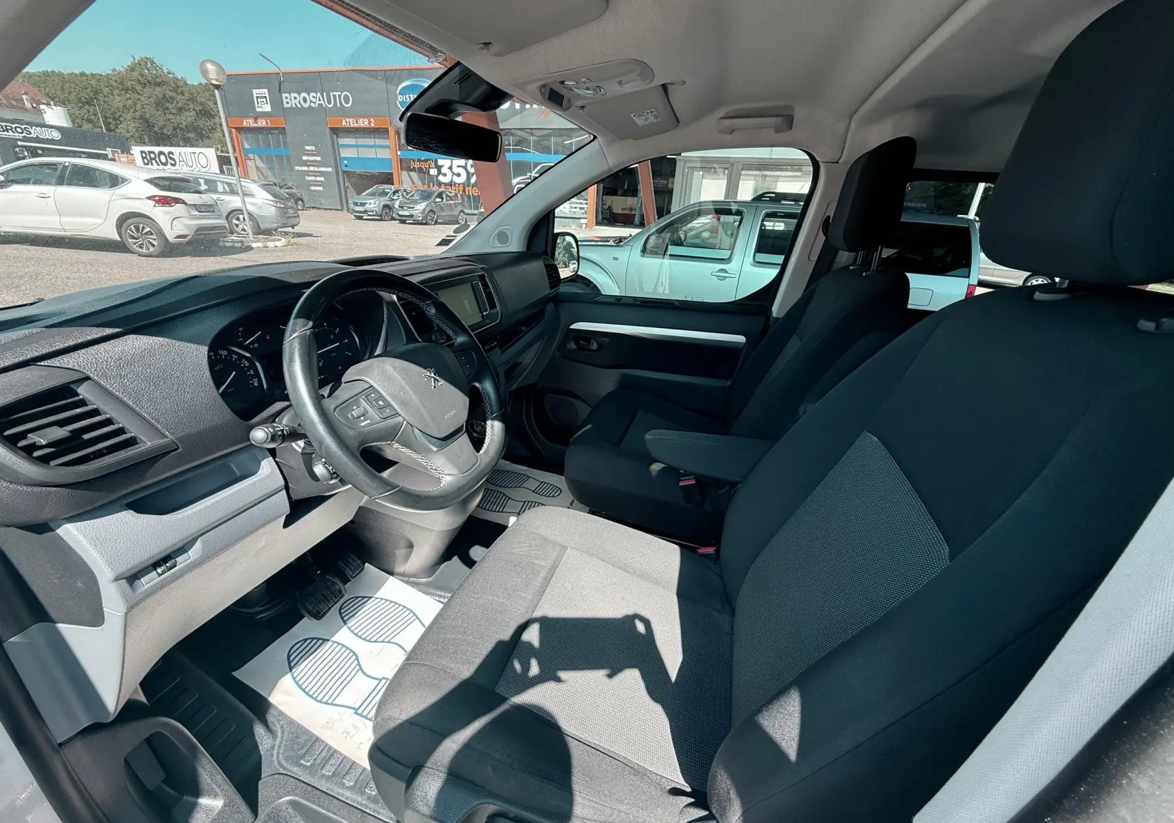 Vue intérieure côté conducteur du Peugeot Expert cabine approfondie 2022 avec sièges tissu gris et volant noir.