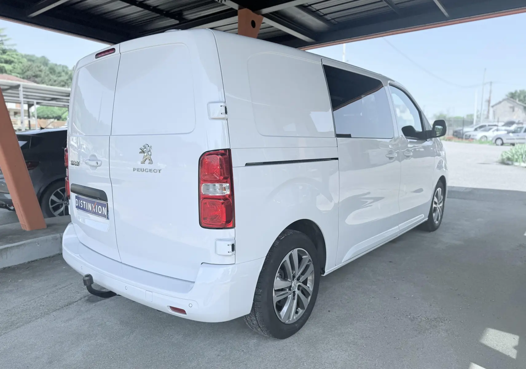 Vue 3/4 arrière droite d’un Peugeot Expert cabine approfondie blanc, avec vitres teintées et attelage visible.