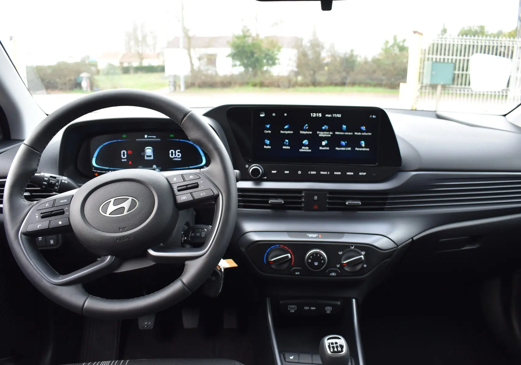 Vue intérieure avant du tableau de bord et volant cuir noir de la Hyundai i20 2025 avec écran tactile central.