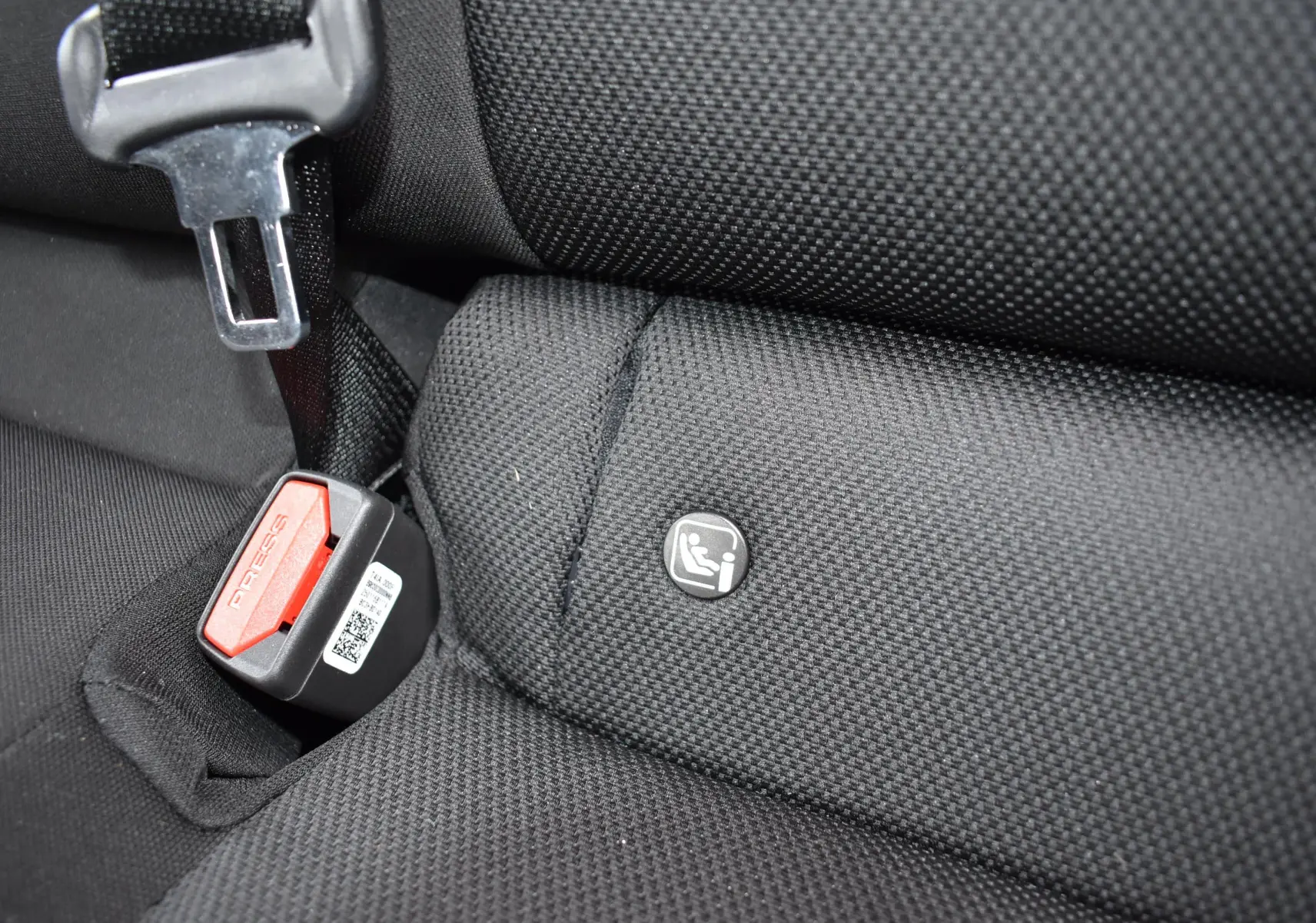 Gros plan sur la banquette arrière noire de la Hyundai i20 2025, montrant l'attache Isofix et la boucle de ceinture rouge.