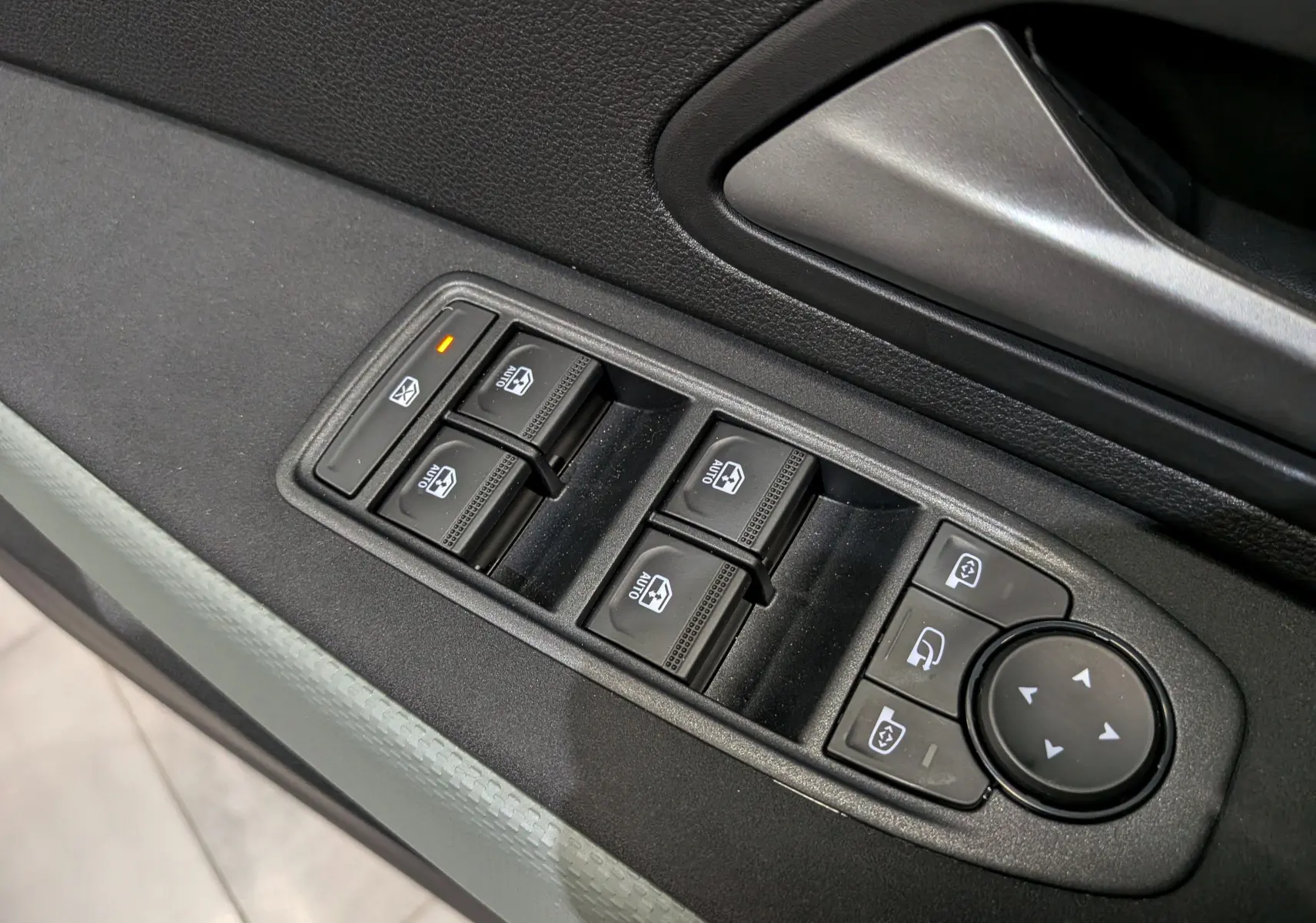 Gros plan sur les commandes de lève-vitres et rétroviseurs côté conducteur du Dacia Bigster bleu indigo.