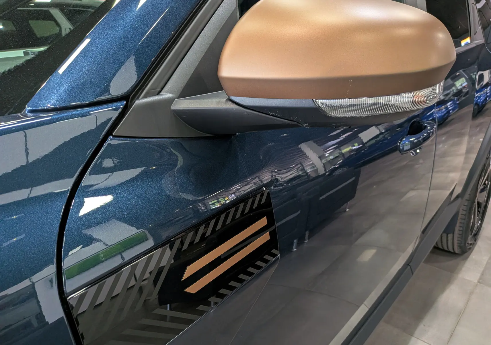 Gros plan sur le rétroviseur couleur bronze et la portière bleu indigo côté gauche du Dacia Bigster 2026.