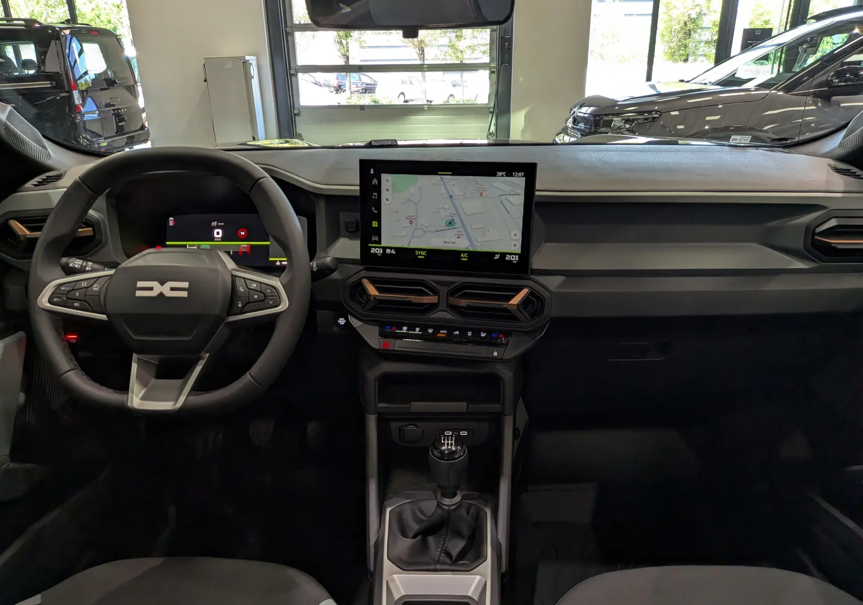 Vue intérieure frontale du tableau de bord du Dacia Bigster 2026 avec écran tactile central et volant multifonction noir.