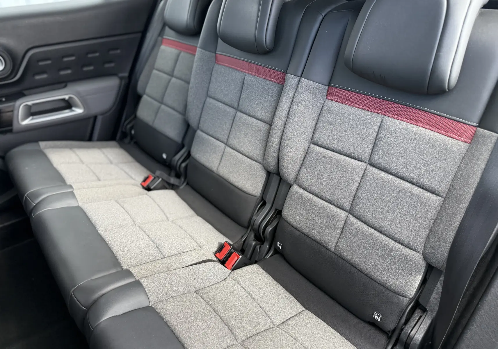Vue intérieure des sièges arrière du Citroën C5 Aircross 2021, tissu gris avec bande rouge et garnitures noires.