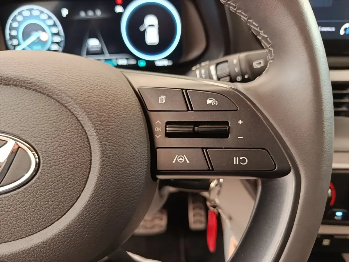 Gros plan sur le volant cuir gris du Hyundai Bayon 2024, avec commandes multifonctions et tableau de bord numérique en arrière-plan.