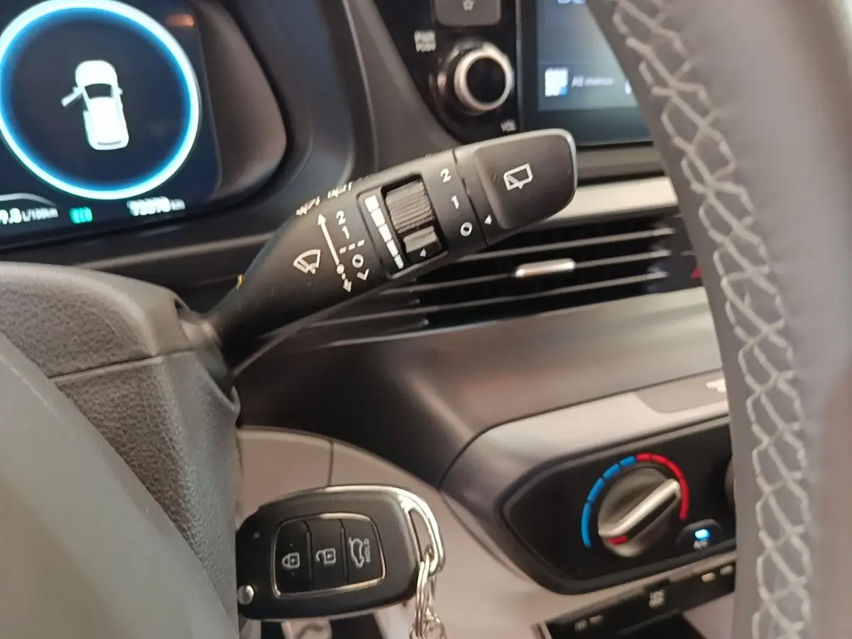 Gros plan sur la commande d’essuie-glace et le tableau de bord noir du Hyundai Bayon blanc, version hybride 2024.