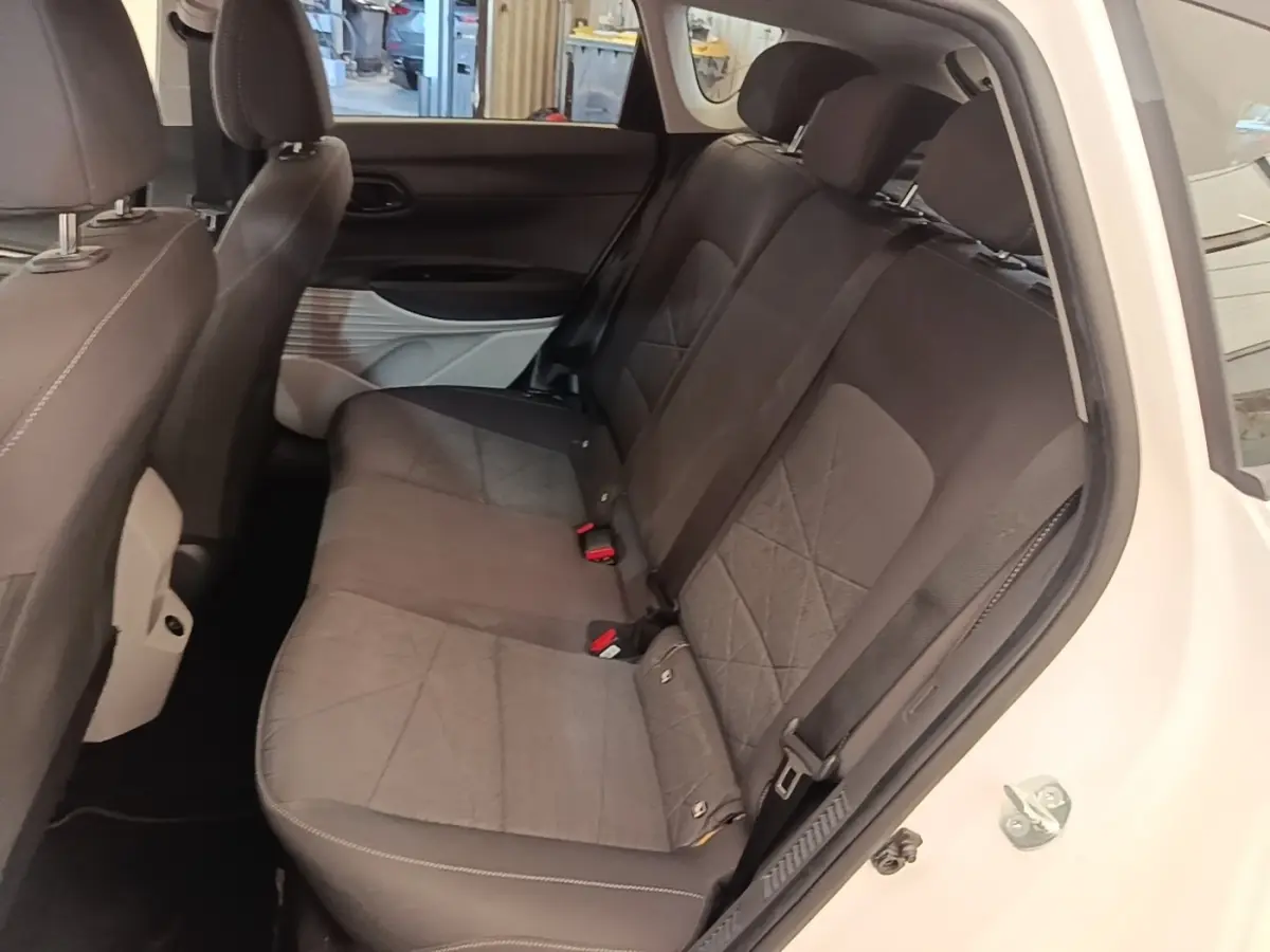 Vue intérieure côté droit des sièges arrière gris foncé d'un Hyundai Bayon blanc, avec ceinture et porte ouvert.