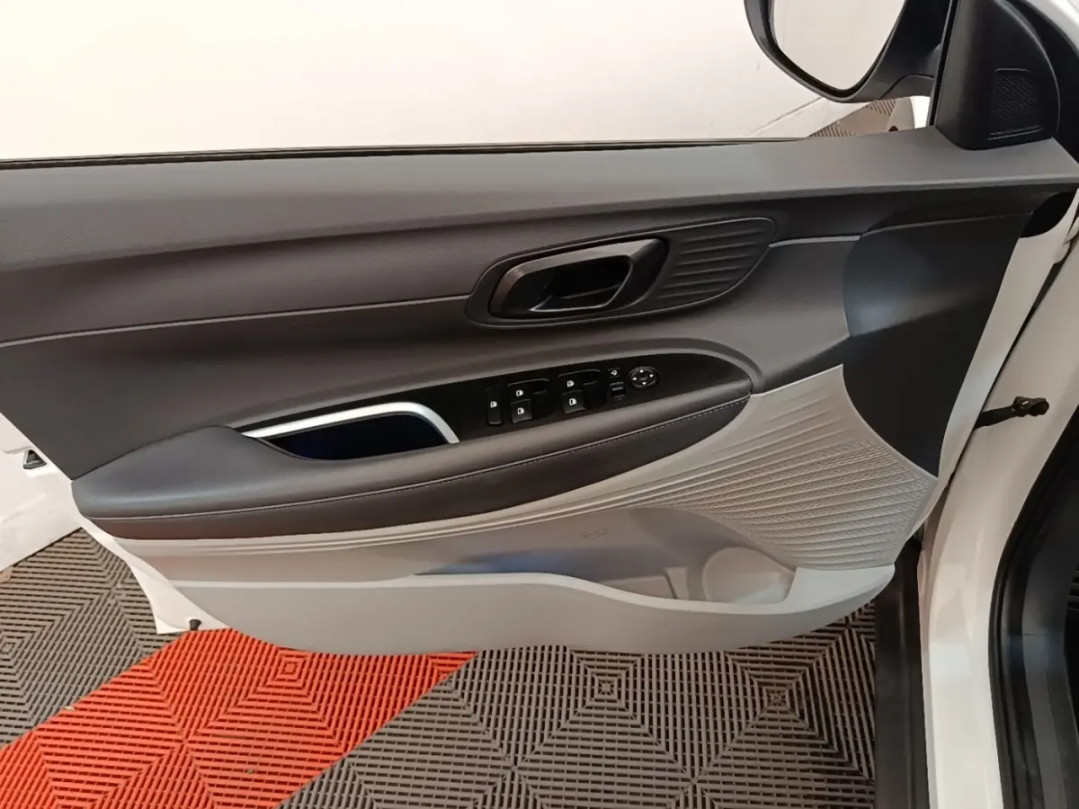 Vue intérieure de la porte avant gauche blanche du Hyundai Bayon 2024, avec commandes électriques et habillage bicolore gris et noir.
