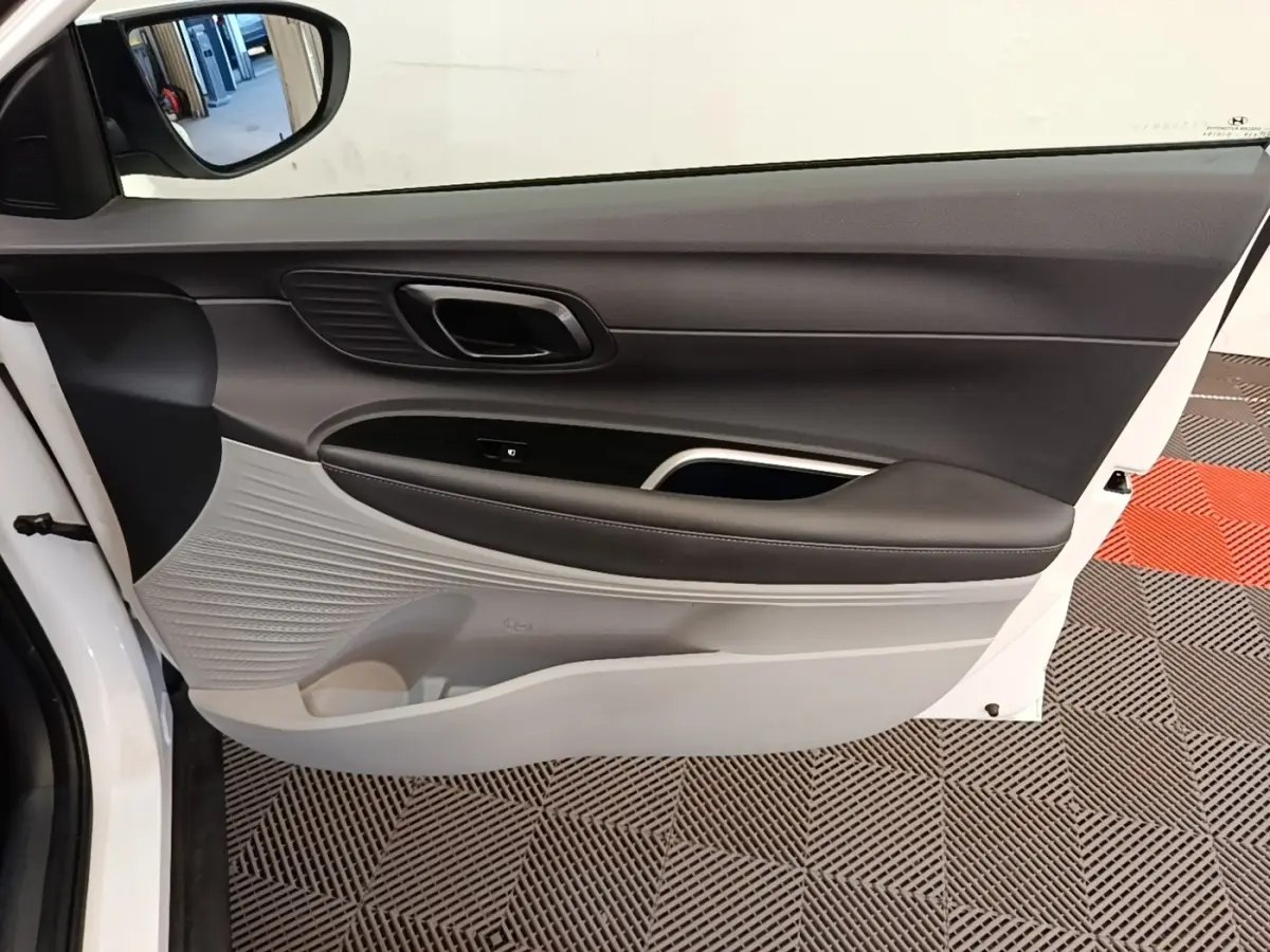 Vue intérieure de la porte avant gauche blanche du Hyundai Bayon 2024 avec garniture bicolore noire et grise.