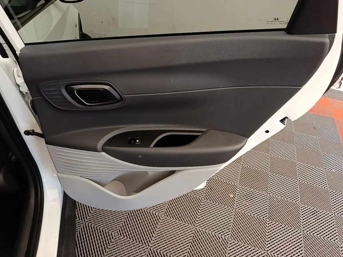 Vue rapprochée de la porte arrière gauche blanche du Hyundai Bayon 2024 avec garniture intérieure noire et grise.