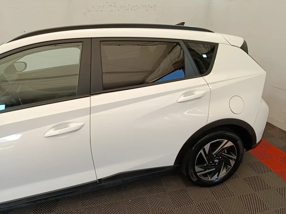 Vue latérale droite d'une Hyundai Bayon blanche, mettant en valeur les jantes noires et le toit noir contrastant.