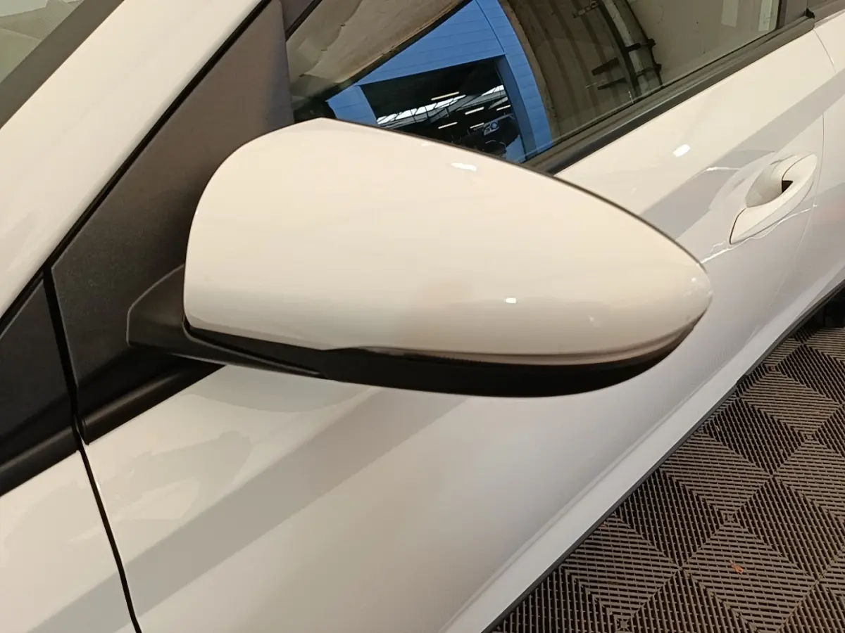 Rétroviseur côté conducteur blanc de Hyundai Bayon 2024, vue rapprochée sur la portière et poignée.