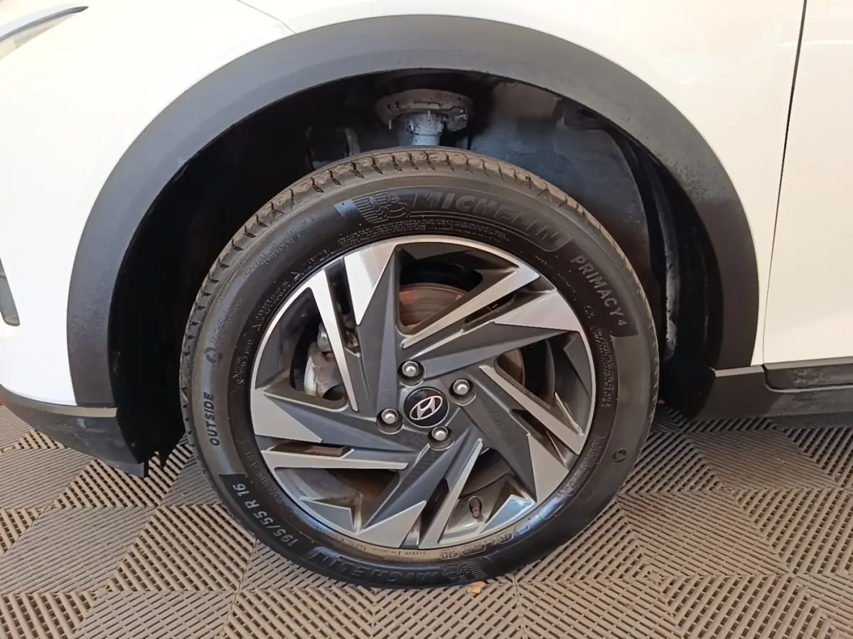 Gros plan sur la roue avant gauche d’une Hyundai Bayon blanche avec jante alliage au design géométrique.